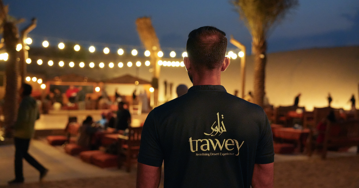 Trawey Tours guide overlooks an authentic, well-lit desert safari camp at night, ensuring a safe and high-quality experience for guests.