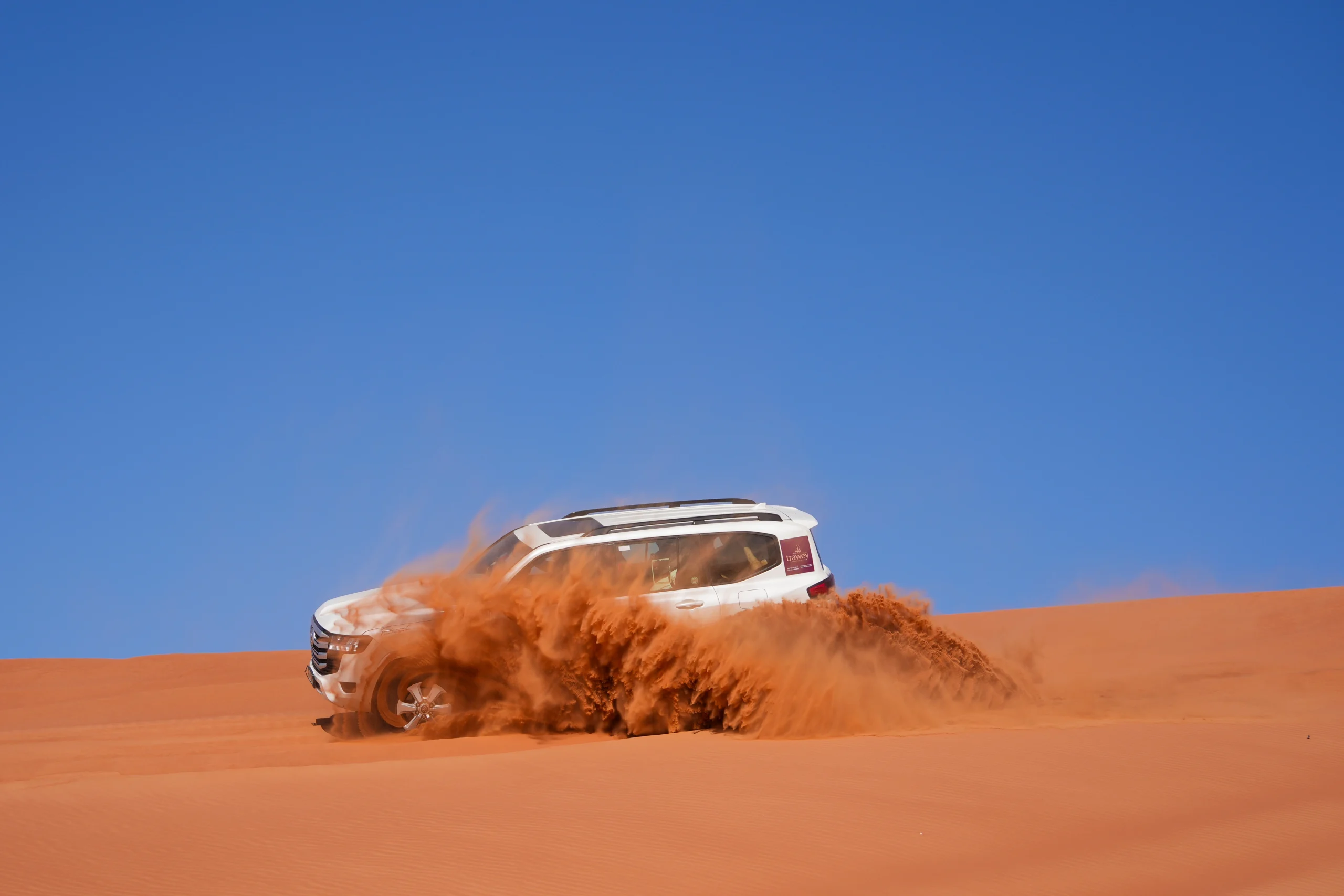 White 4x4 vehicle dune bashing in Dubai, illustrating the thrilling off-road maneuvers that can cause motion sickness.