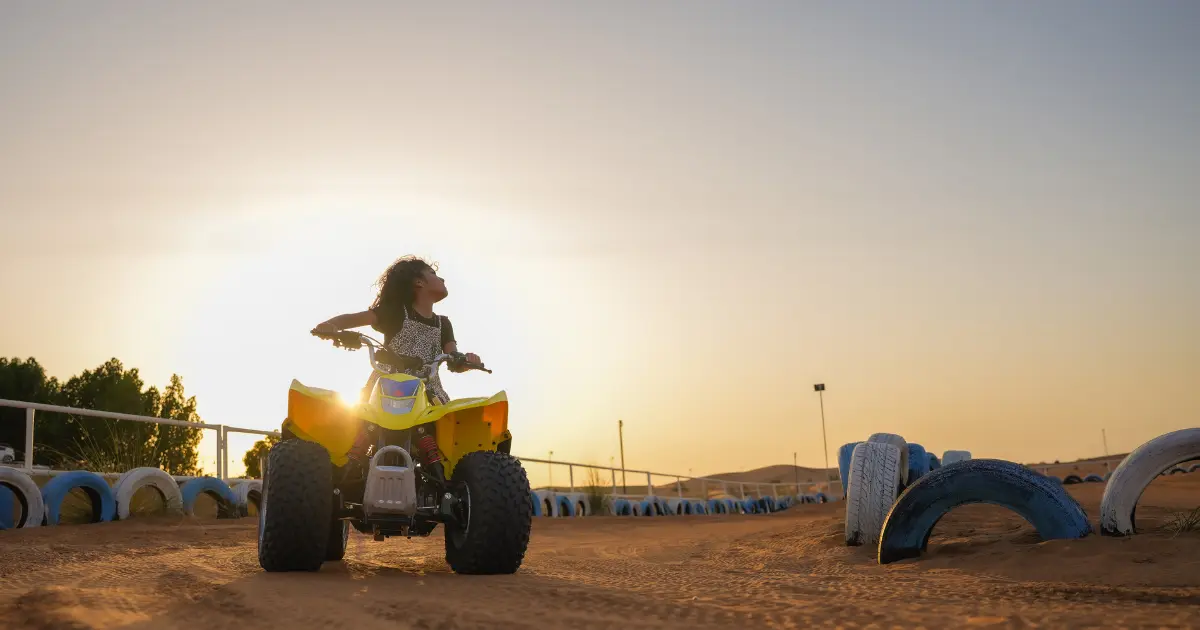 Child enjoying mini quad biking on a safe, fenced track during a kid-friendly desert safari with Trawey Tours.