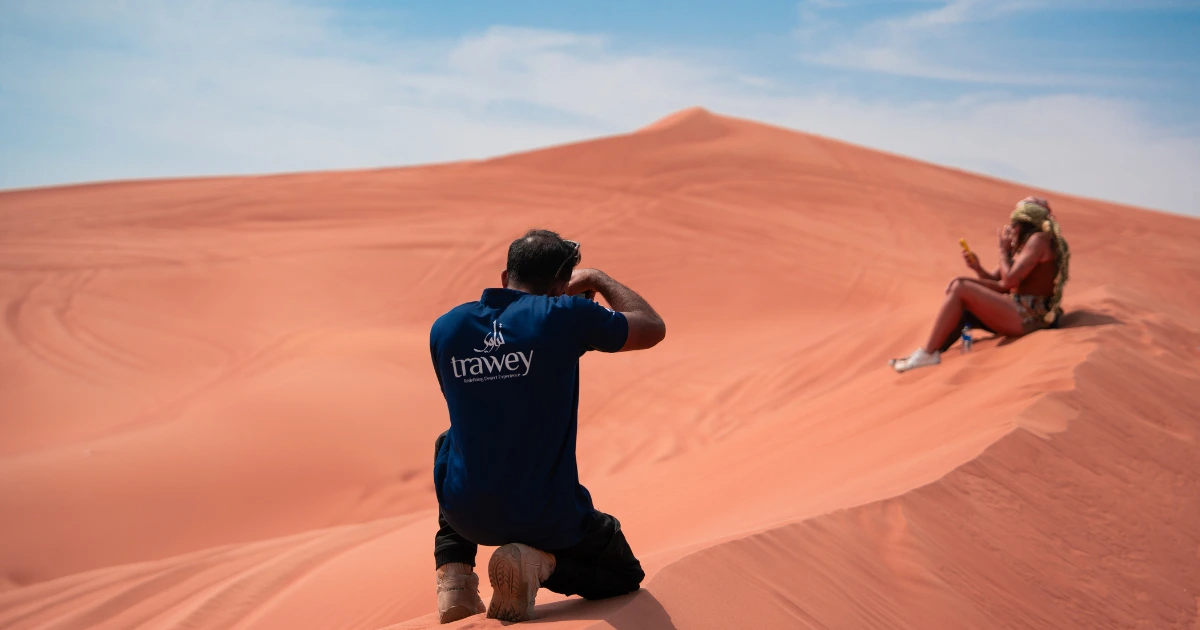 Trawey guide taking guest photo in red sand