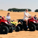 A family of four enjoying a quad biking adventure on sand dunes during a desert safari.
