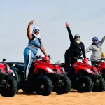 Family of five riding red and yellow quad bikes during a premium desert safari upgrade.