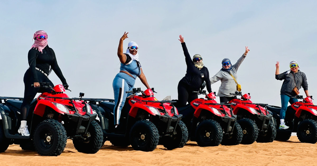 Family of five riding red and yellow quad bikes during a premium desert safari upgrade.