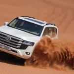 Licensed Trawey Tours driver performing a controlled dune bashing maneuver in a white Land Cruiser.